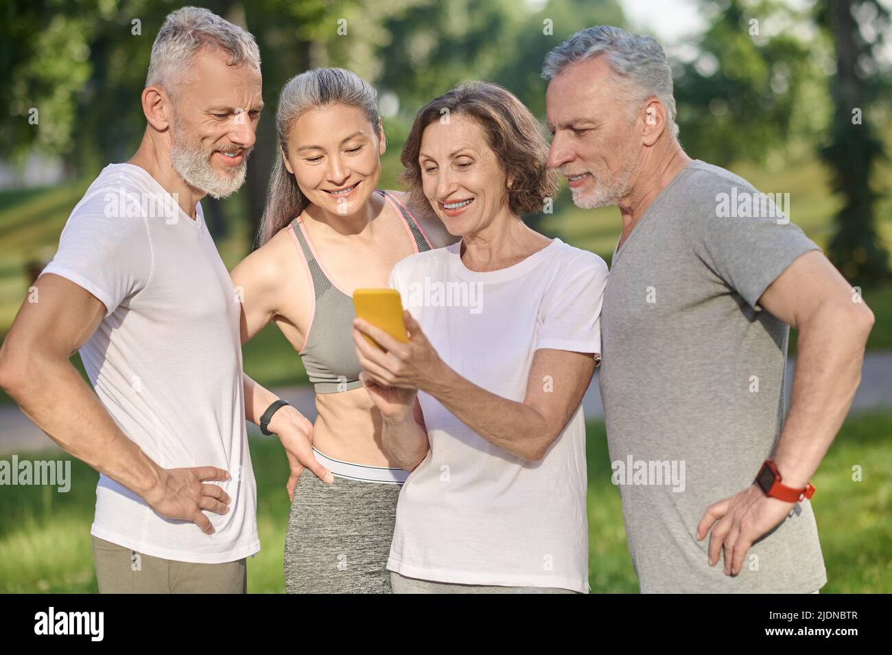 Gruppo di persone che guardano le foto in uno smartphone Foto Stock