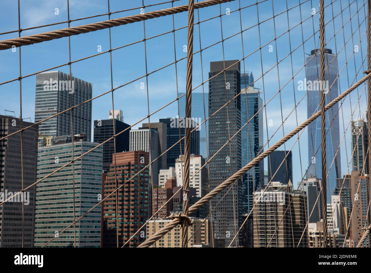 Alti edifici di Lower Manhattan dietro il ponte di Brooklyn pedone Walkway Structual Wires a New York City, Stati Uniti d'America Foto Stock