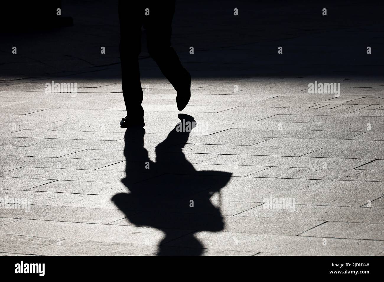 Silhouette di donna solitaria a piedi con borsa lungo la strada, ombra nera sul marciapiede. Concetto di solitudine, vita cittadina Foto Stock