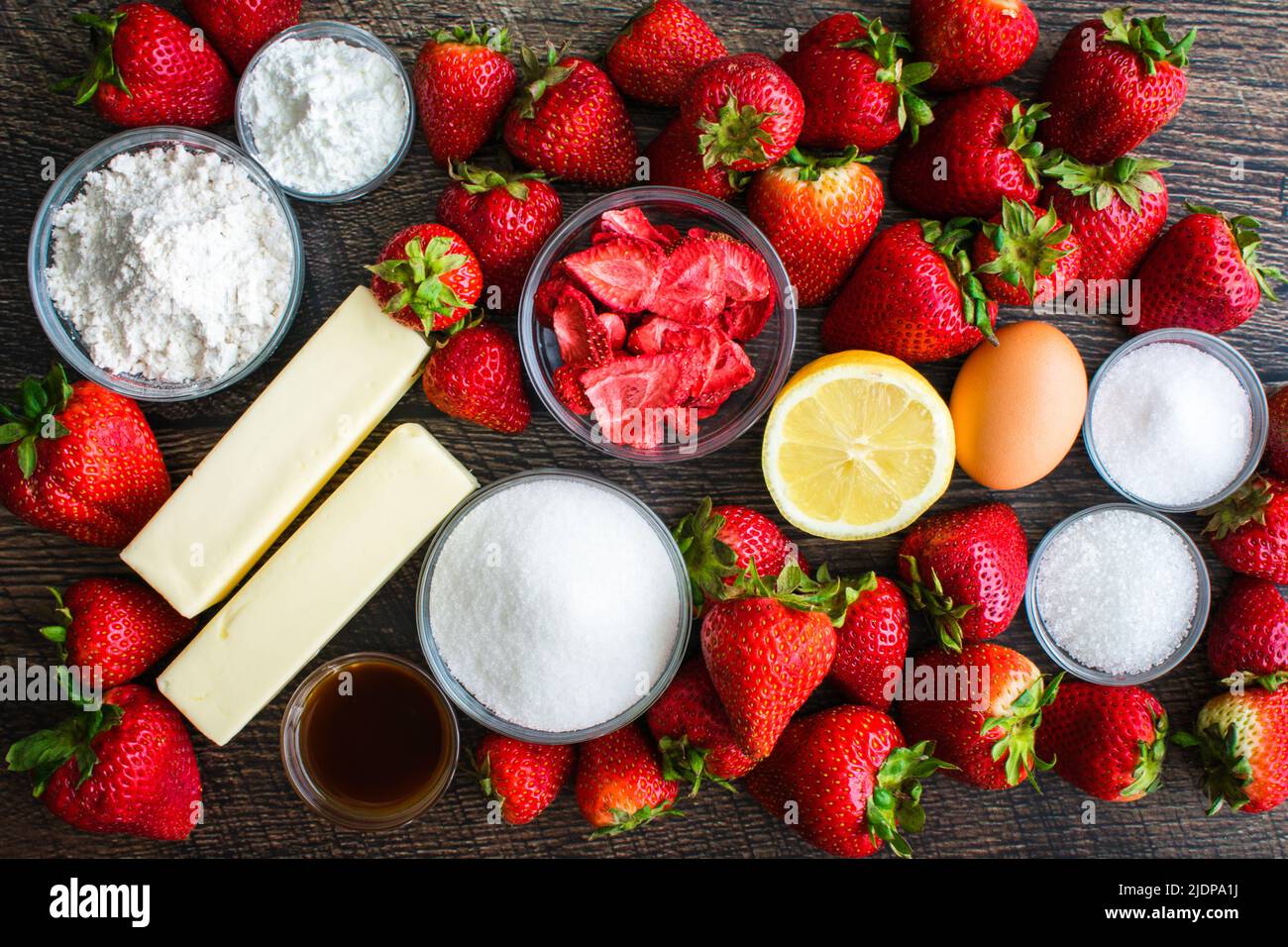 Vista dall'alto degli ingredienti per una torta di fragole con una crosta di fragole: Fragole fresche, farina, zucchero e altri ingredienti di pasticceria Foto Stock