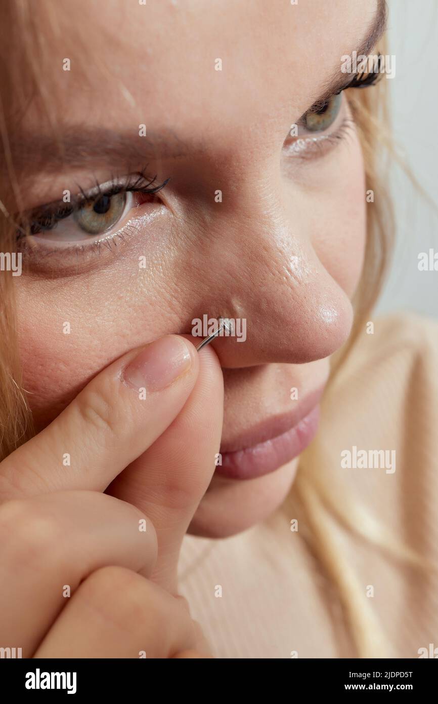 Primo piano del visage di una giovane donna con piercing appeso al naso Foto Stock