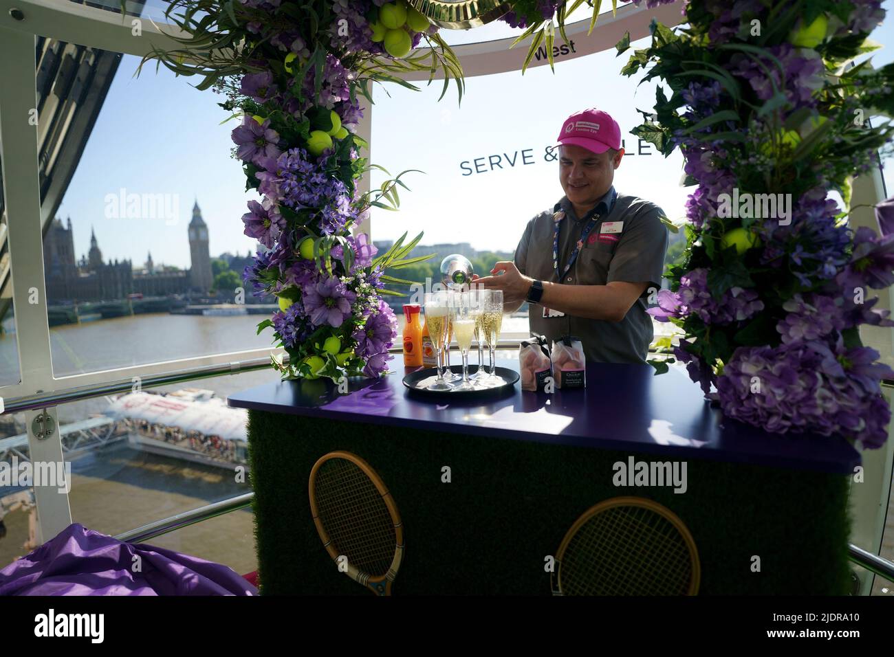 Un assistente serve champagne all'interno di una cialda sul London Eye lastminute.com, che è stato deocarted con un tema Wimbledon prima dell'inizio della competizione di tennis la prossima settimana. Data foto: Mercoledì 22 giugno 2022. Foto Stock