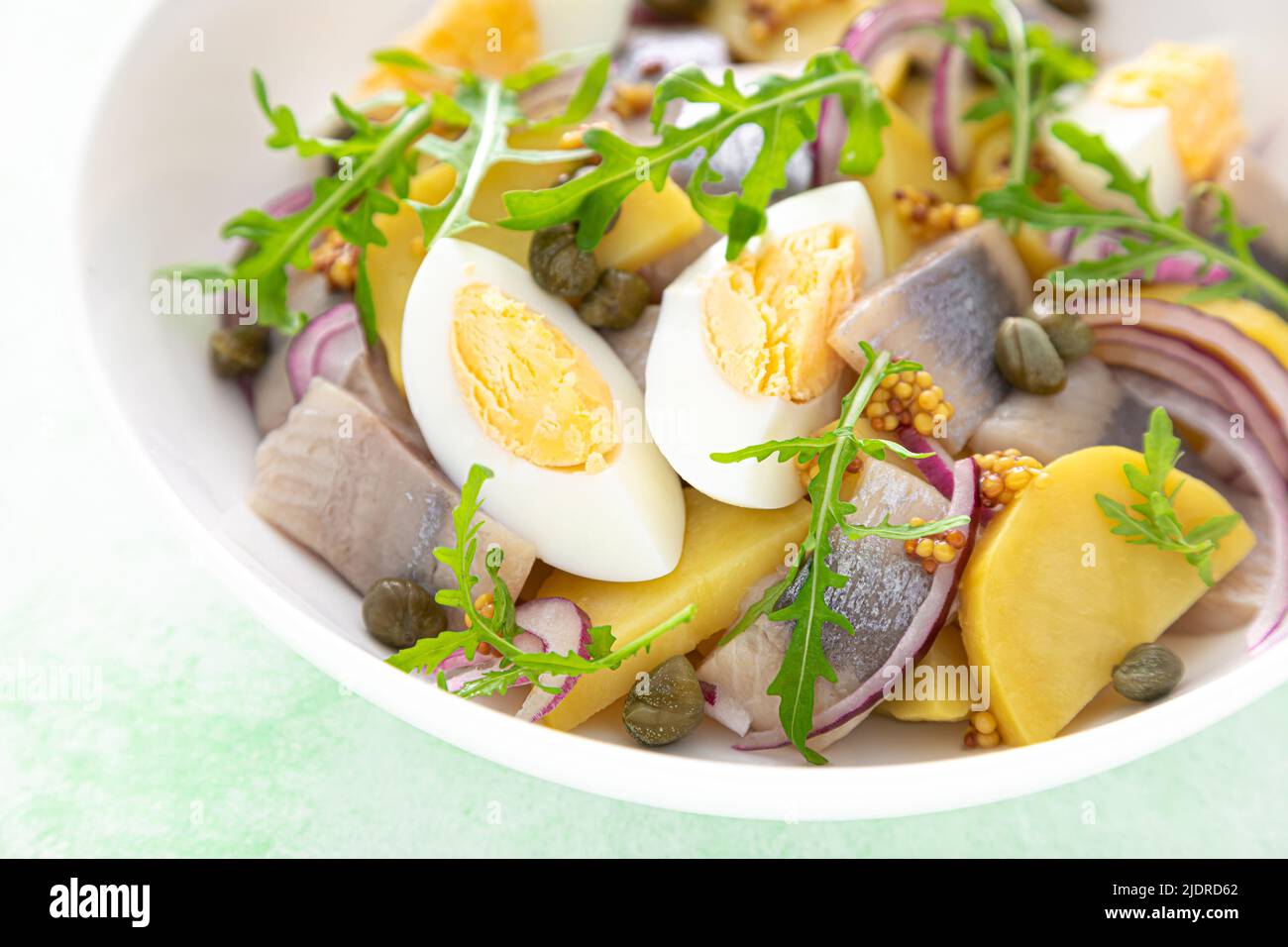 Insalata di aringhe e patate bollite con uova, capperi e cipolla rossa Foto Stock