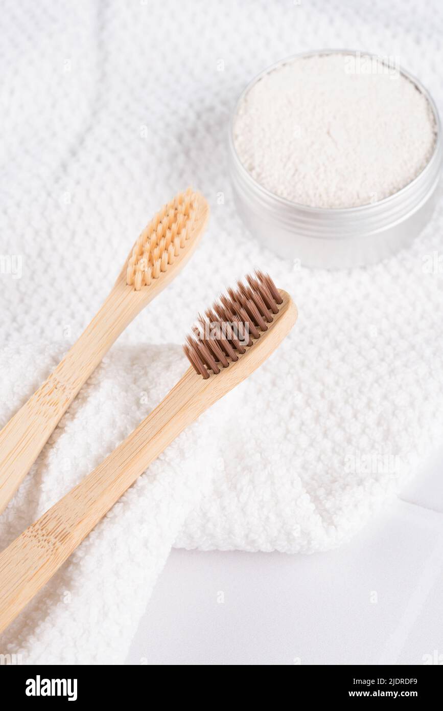 Immagine verticale con spazzolini da denti in bambù con polvere minerale caolino in alluminio su sfondo di piastrelle bianche. Prodotti da bagno naturali, biologici d Foto Stock