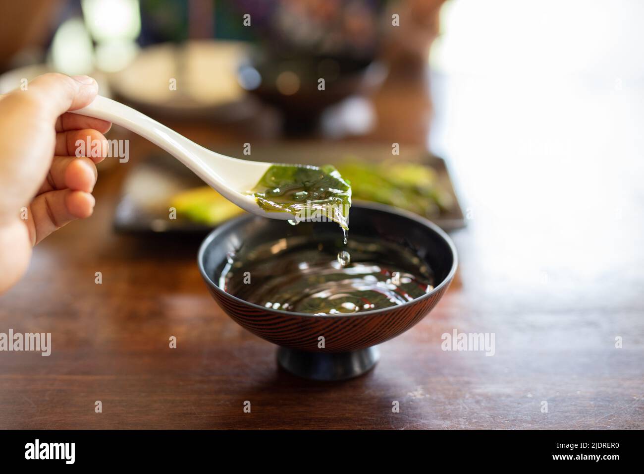 Mano con cucchiaio che mangia la zuppa giapponese tradizionale delle alghe. Foto Stock