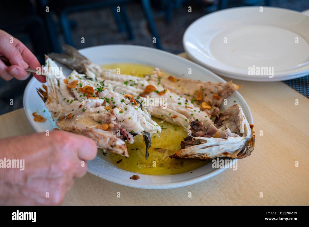 Serve in ristorante di pesce fresco alla griglia con aglio e olio d'oliva su vecchi parrillas di pesce branzino al piccolo villaggio di pescatori Getaria, basco Foto Stock
