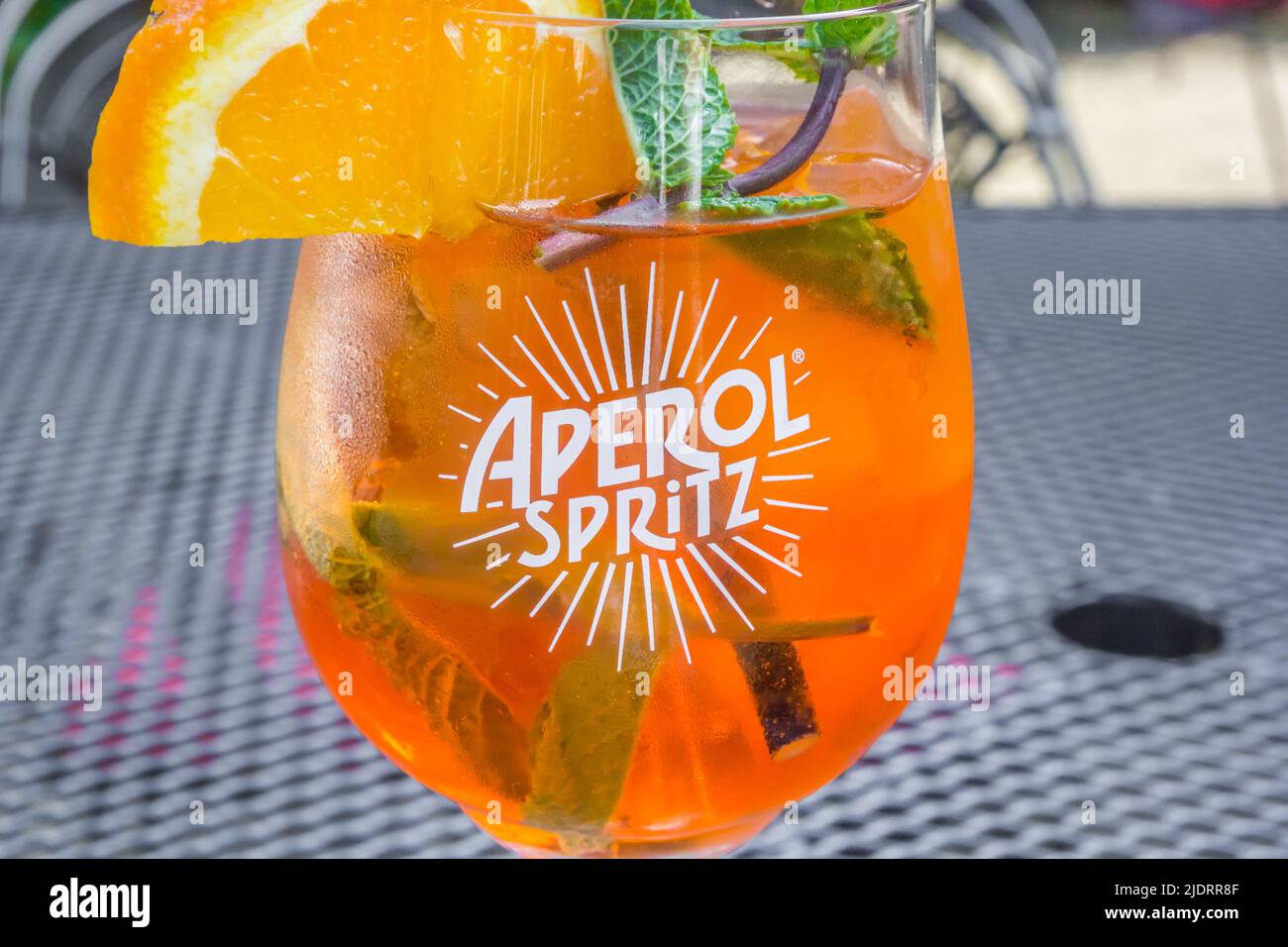 Bicchiere di Aperol Spritz con una fetta di arancia e menta fresca in un caffè Foto Stock