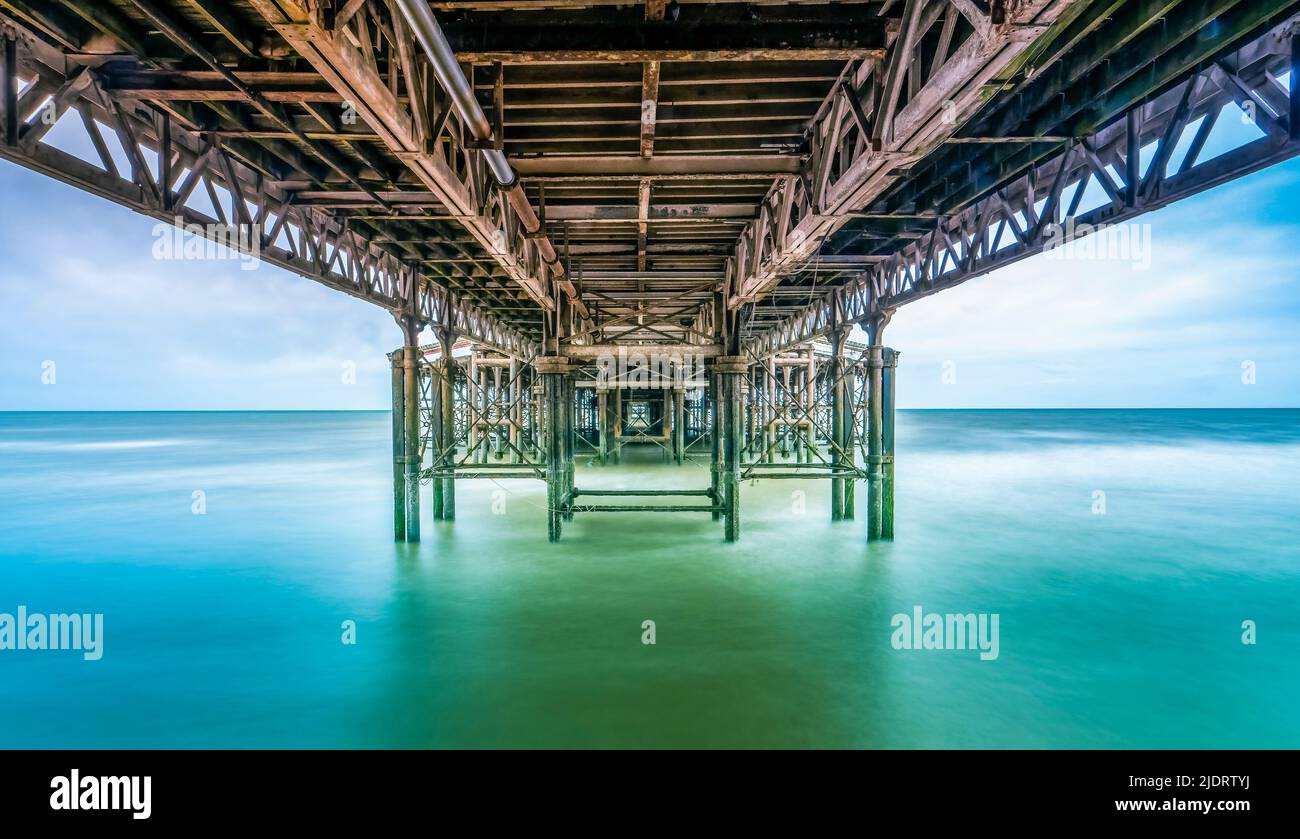 La fotografia a lunga esposizione cattura la parte inferiore del molo centrale a Blackpool, Lancashire, Regno Unito, in alta marea con il mare che guarda liscio e sfocato Foto Stock