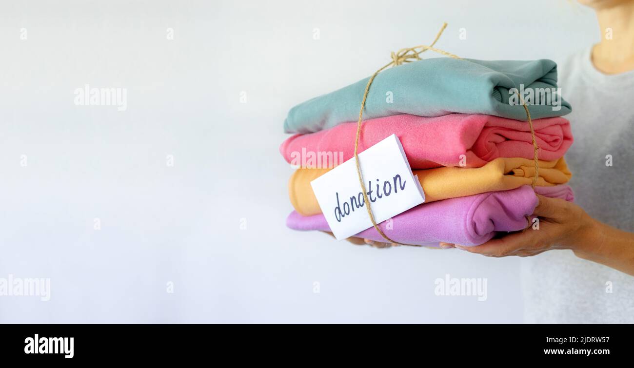Mano della donna che tiene una pila di vestiti. Donazione di vestiti, Concept.Preparing di indumento a casa prima di donare Foto Stock