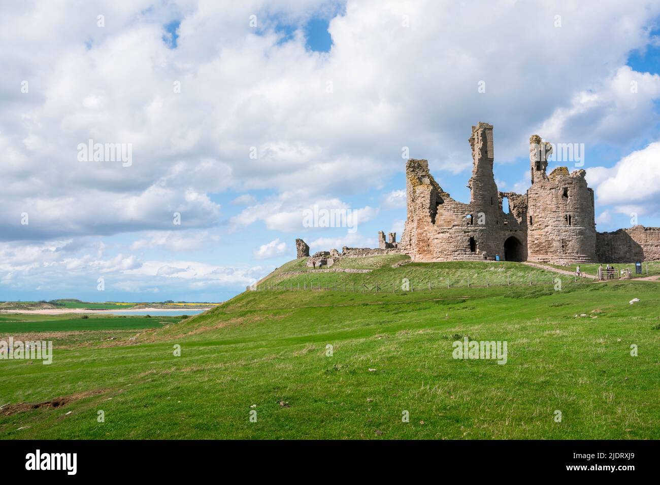 Castello rovine UK, vista del castello di Dunstanburgh 14th secolo in rovina, situato sulla costa Northumberland vicino a Embleton Bay, Inghilterra Foto Stock