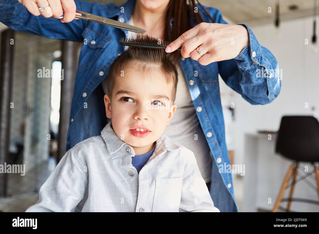 Madre o parrucchiere che taglia i capelli del bambino a casa o nel salone dei capelli Foto Stock