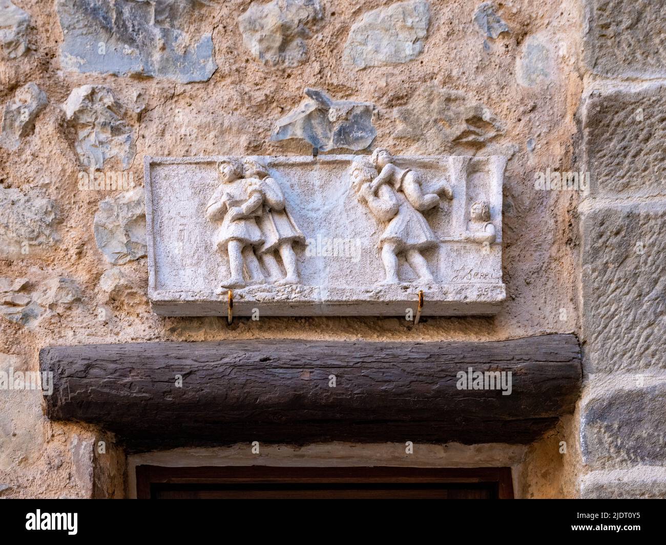 Un pannello in pietra intagliato con 5 figure adorna l'ingresso di una casa in pietra nel villaggio di Villars sur Var nelle Alpi Marittime del sud-est della Francia Foto Stock