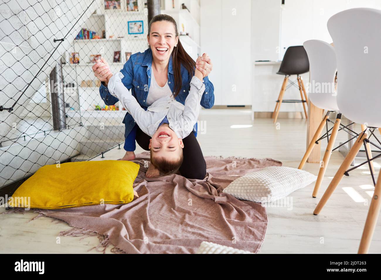 Madre felice che si imbrogliava con il figlio che ride nel soggiorno di casa Foto Stock