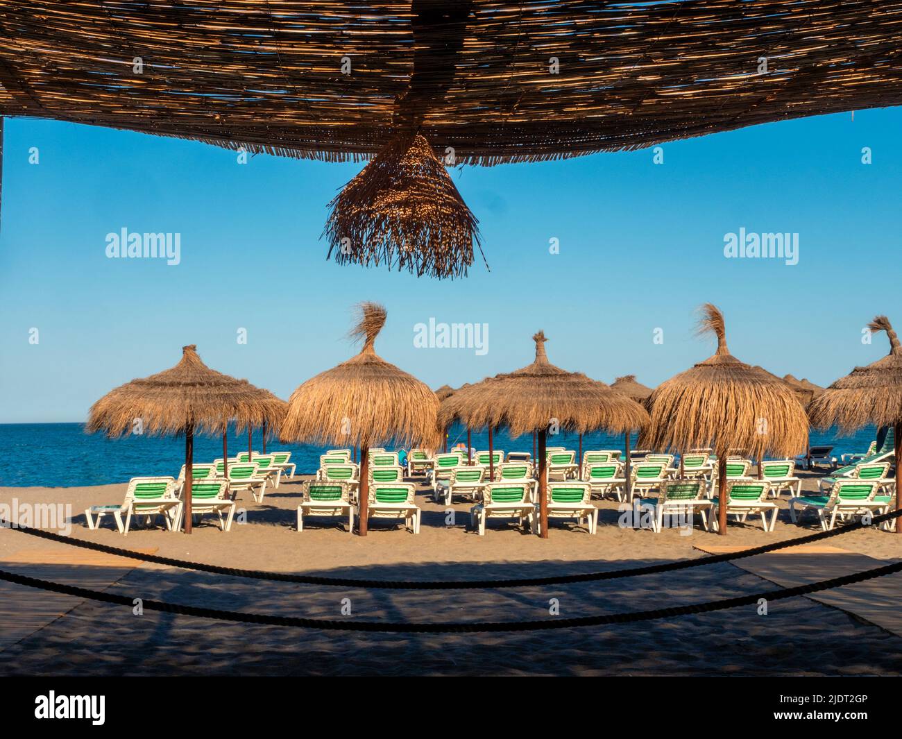 Ombra sotto le pergolas di canna accanto ai lettini e ombrelloni Foto Stock