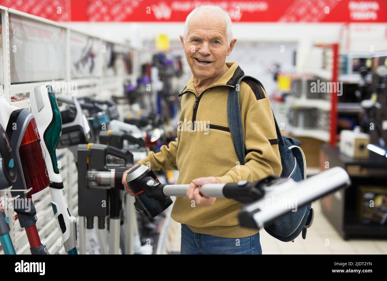 Senor man pensionato che acquista Upright Vacuum Cleaner in showroom del negozio di elettrodomestici Foto Stock