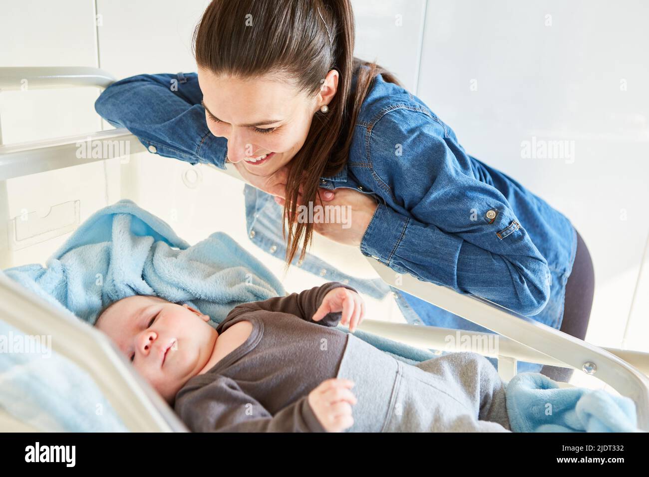 Madre single felice guardando il suo bambino a letto come concetto di amore materno Foto Stock