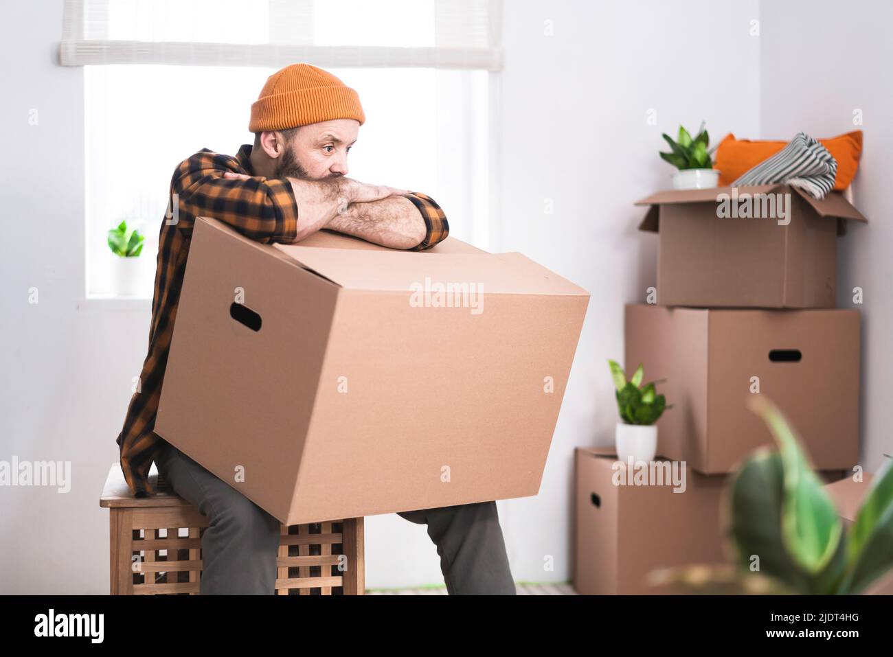Hipster uomo con scatole mobili in nuovo appartamento moderno. Uomo maturo che disimballa le cose dalle scatole mentre si sposta in appartamento nuovo. Foto Stock