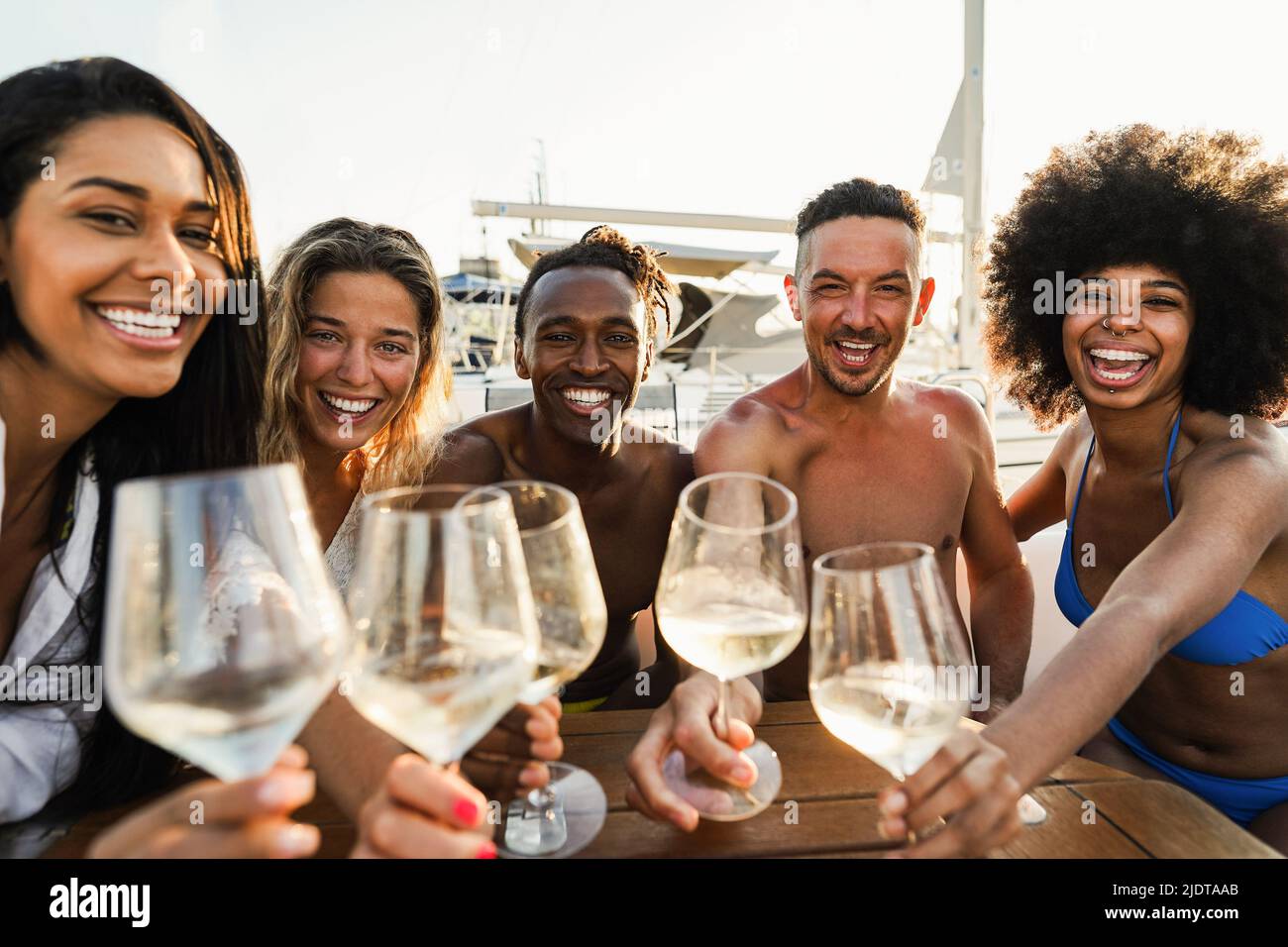 Amici multirazziali che fanno selfie mentre si acclamano con il vino alla festa in barca all'aperto - fuoco sul volto africano dell'uomo Foto Stock