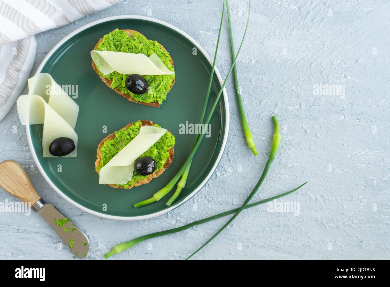 Pane all'aglio. Fette di baguette con aglio burro olive formaggio e aglio frecce in piatto verde Foto Stock