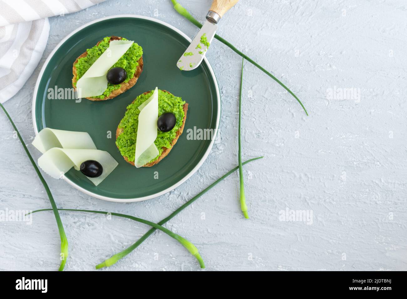 Pane all'aglio. Fette di baguette con aglio burro olive formaggio e aglio frecce in piatto verde Foto Stock
