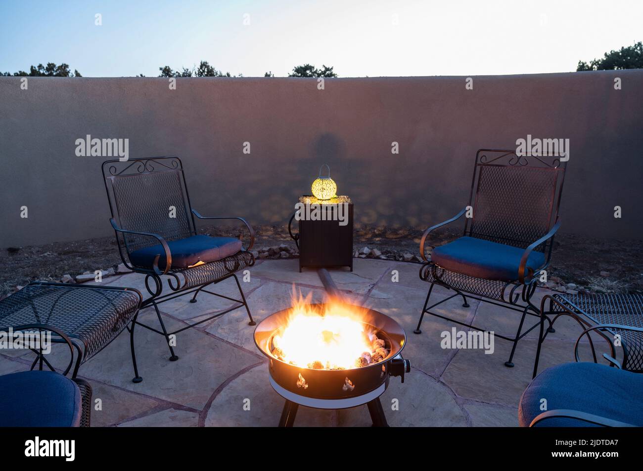 Sedie intorno alla fossa del fuoco del cortile posteriore al crepuscolo Foto Stock