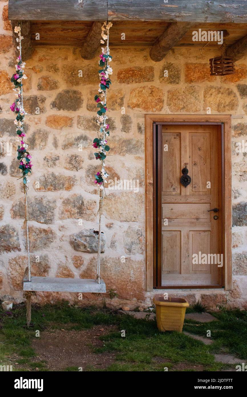 Bella altalena di legno decorata con fiori, all'ingresso della casa turca con una porta di legno, sull'isola di Kekova. Foto Stock