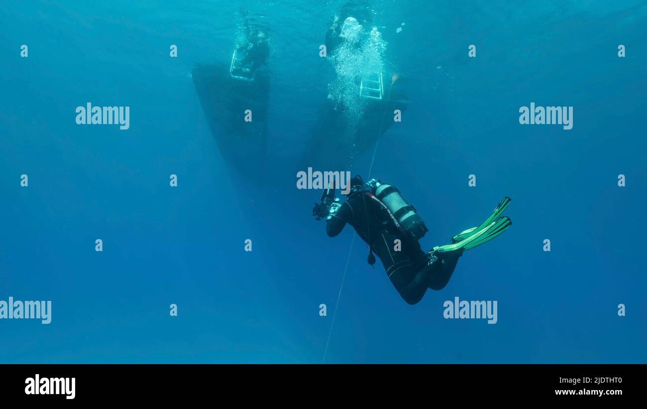 Il subacqueo nuota verso la barca subacquea in acqua blu. Mar Mediterraneo, Cipro Foto Stock