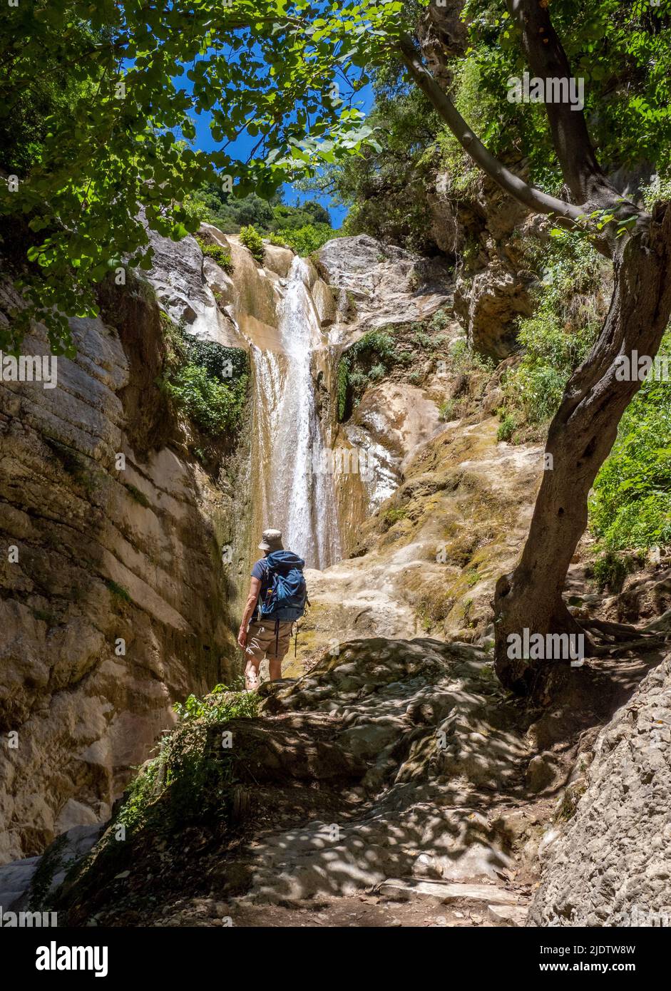 Un camminatore che sale fino alla bellissima cascata di Dimosari sopra Nidri a Lefkada nelle Isole IONIE della Grecia Foto Stock