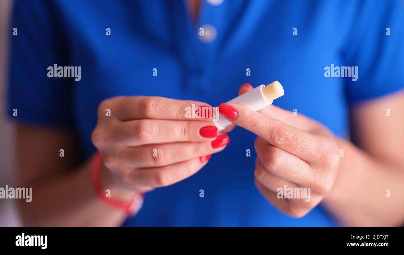 Donna con manicure rosso che tiene il rossetto igienico nelle mani primo piano Foto Stock