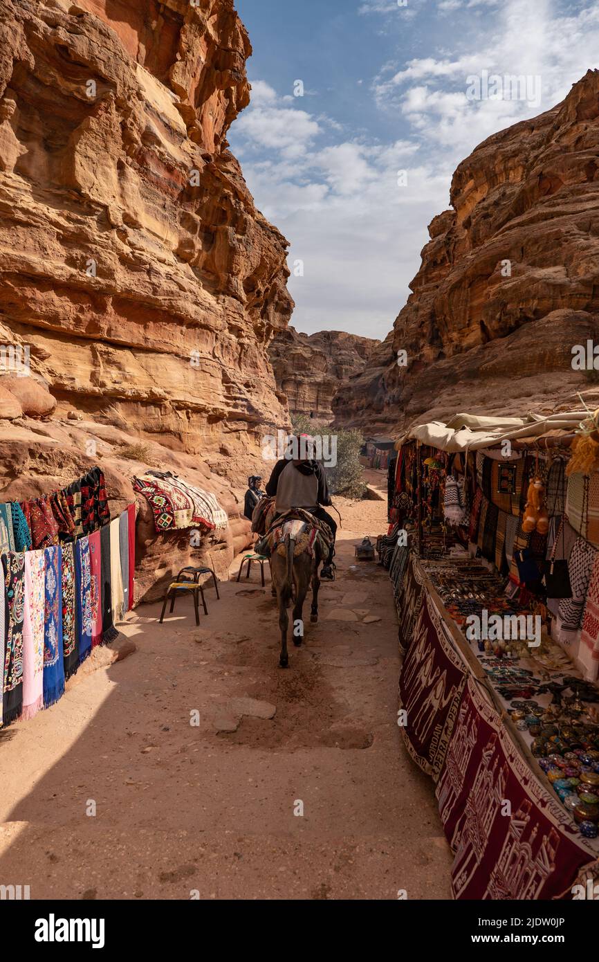 Beduin sull'asino che guida attraverso il mercato locale dei souvenir nell'antica città di Petra, Giordania Foto Stock