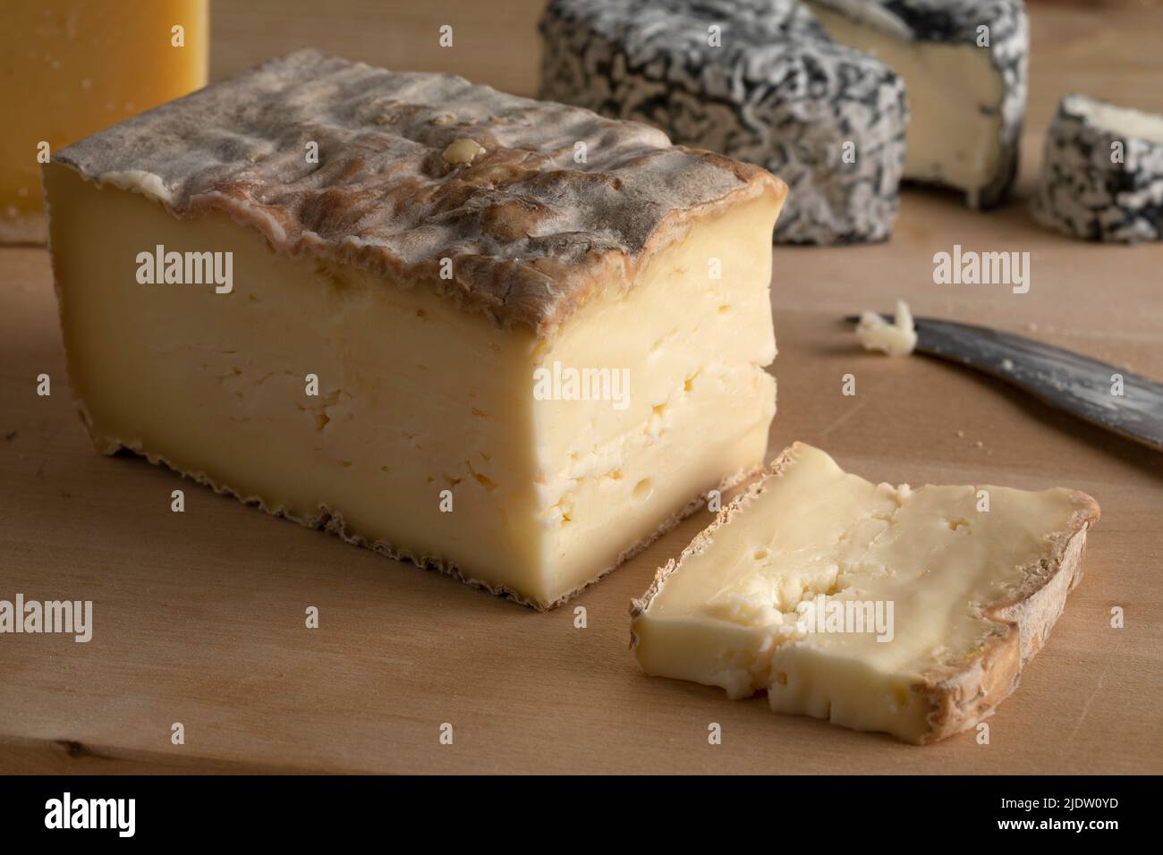 Pezzo di Taleggio italiano e una fetta su un tagliere da vicino Foto Stock