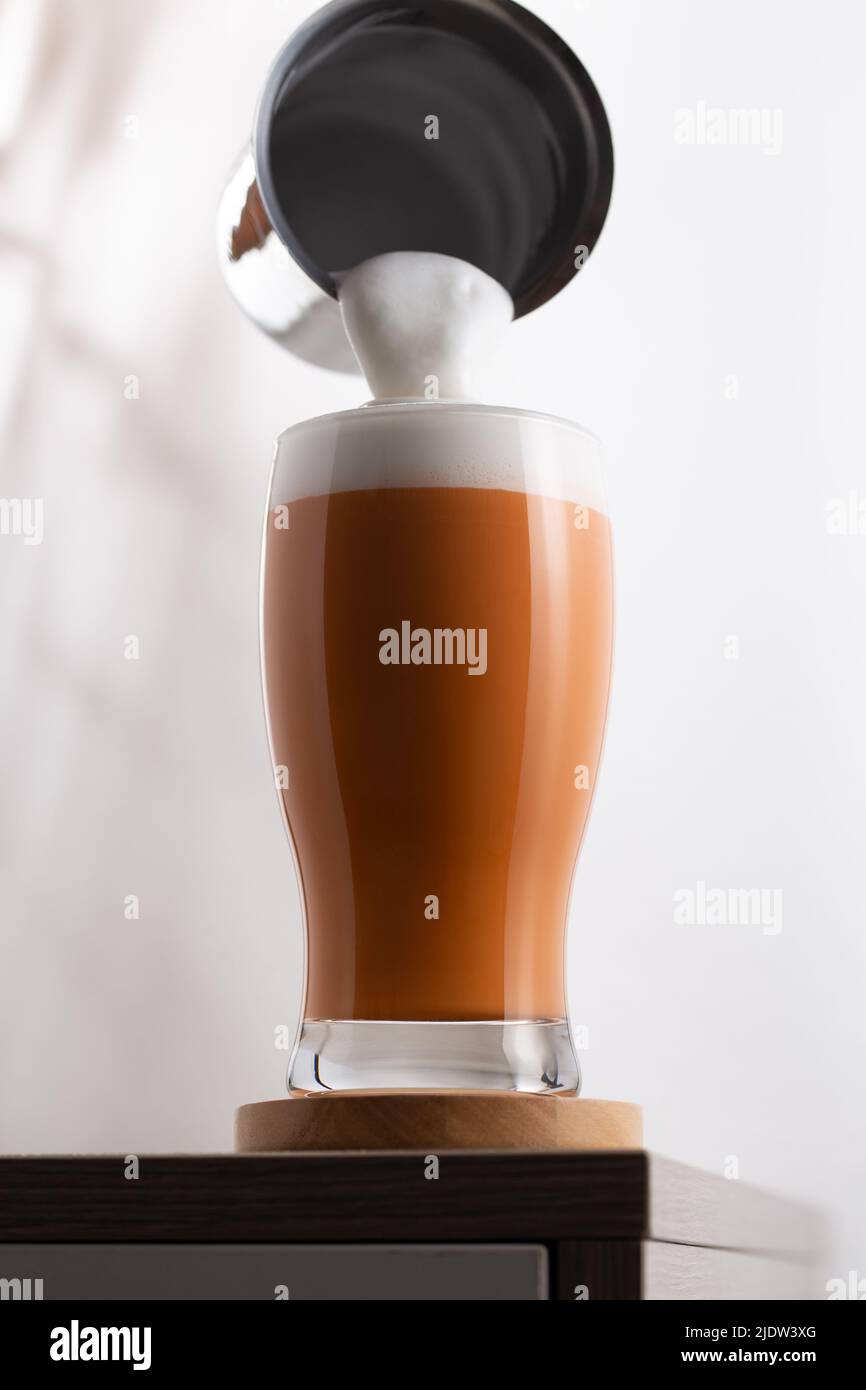 Un bicchiere di tè con latte ghiacciato e schiuma di latte. Versate il latte schiumato sopra il tè al latte nel bicchiere. Foto Stock