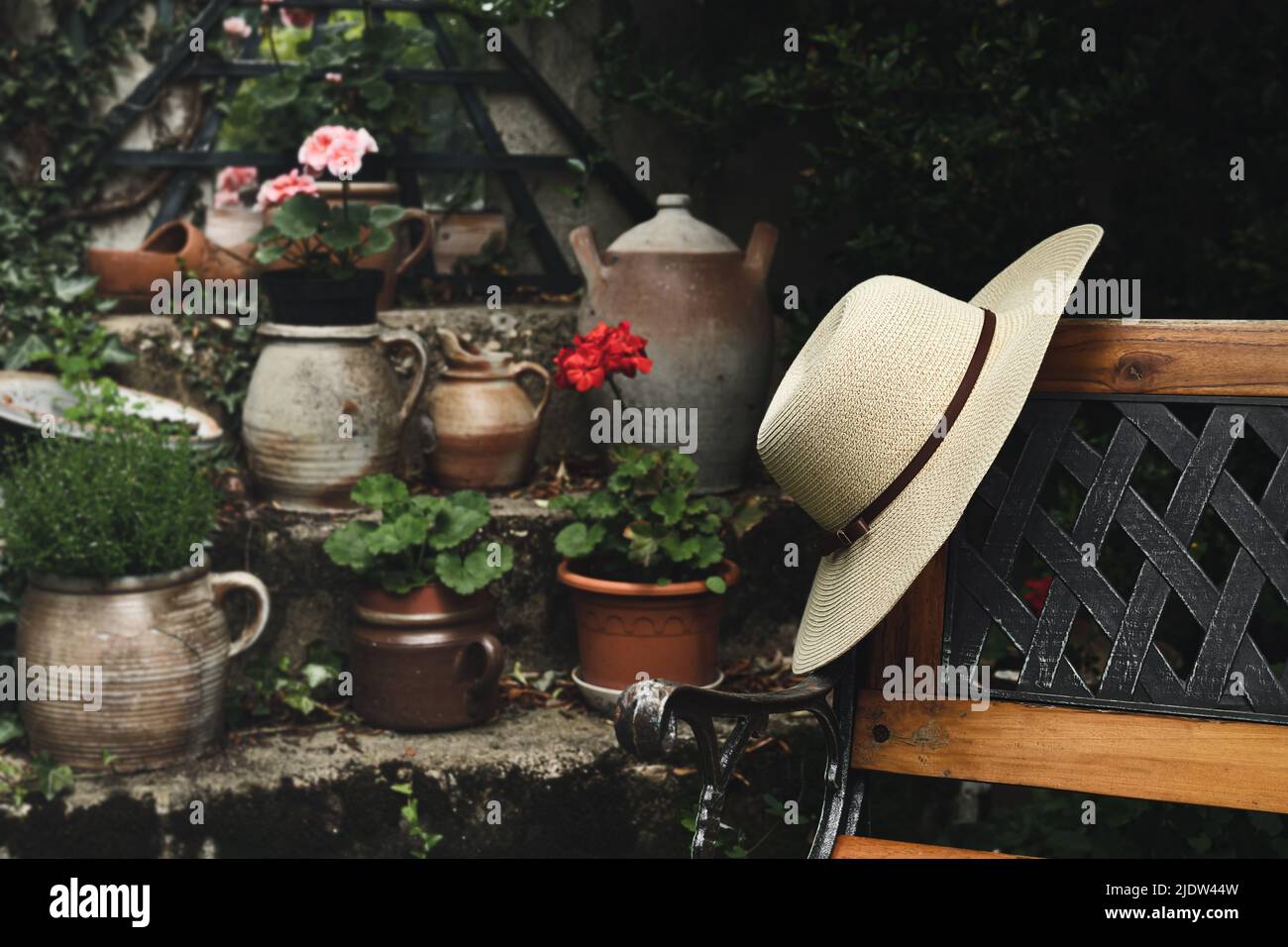 Cappello estivo da donna su una panca in legno in giardino, stile di vita calmo e concetto di cottagecore Foto Stock