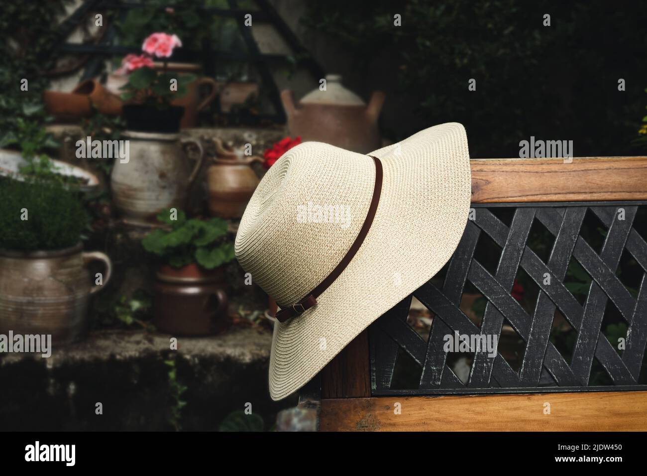 Cappello estivo donna su una panca in legno nel giardino primo piano, pastorale e concetto di vita lenta Foto Stock