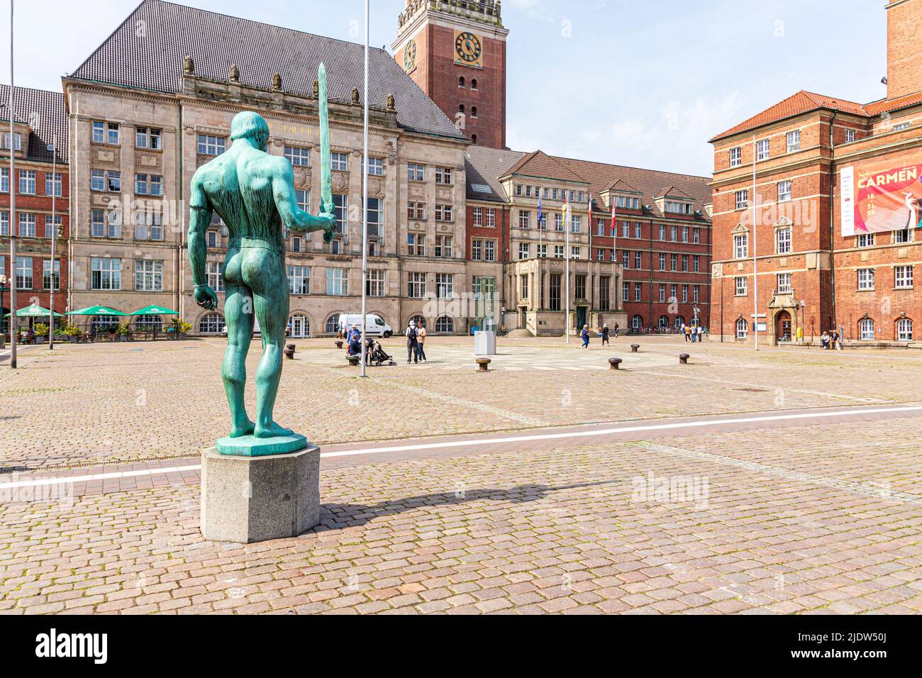 La statua del portatore di spada (Schwertträger) in piazza Kieler Rathausplatz con il Municipio (Landeshauptstadt) e il Teatro dell'Opera di Kiel Foto Stock
