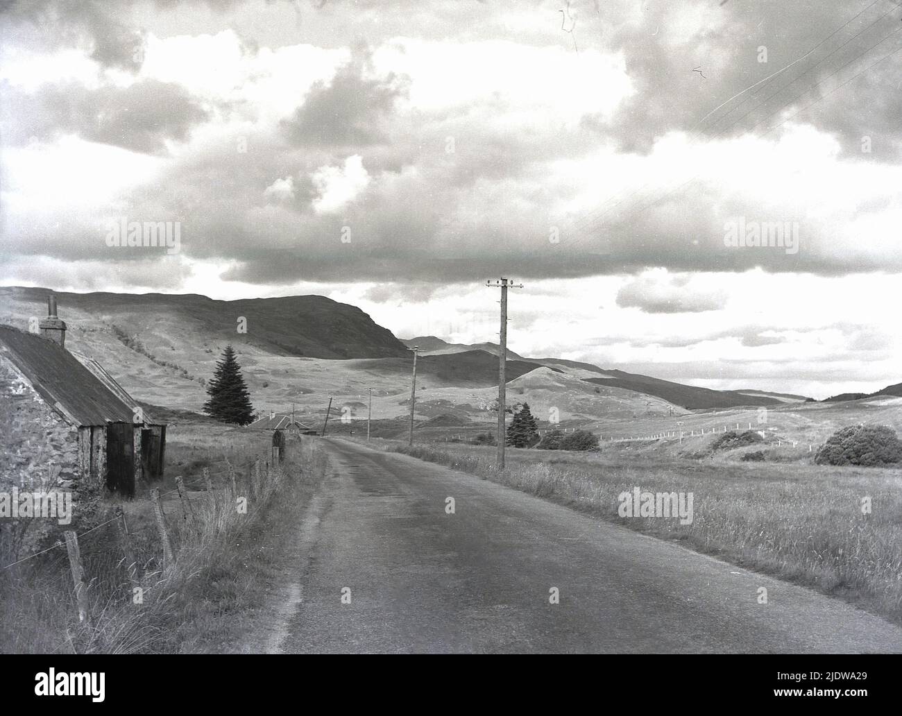 1950s, storico, vecchio cottage abbandonato crocchette accanto a una strada vicino Mallaig nelle colline ondulate delle Highlands scozzesi, Scozia, Regno Unito. Foto Stock