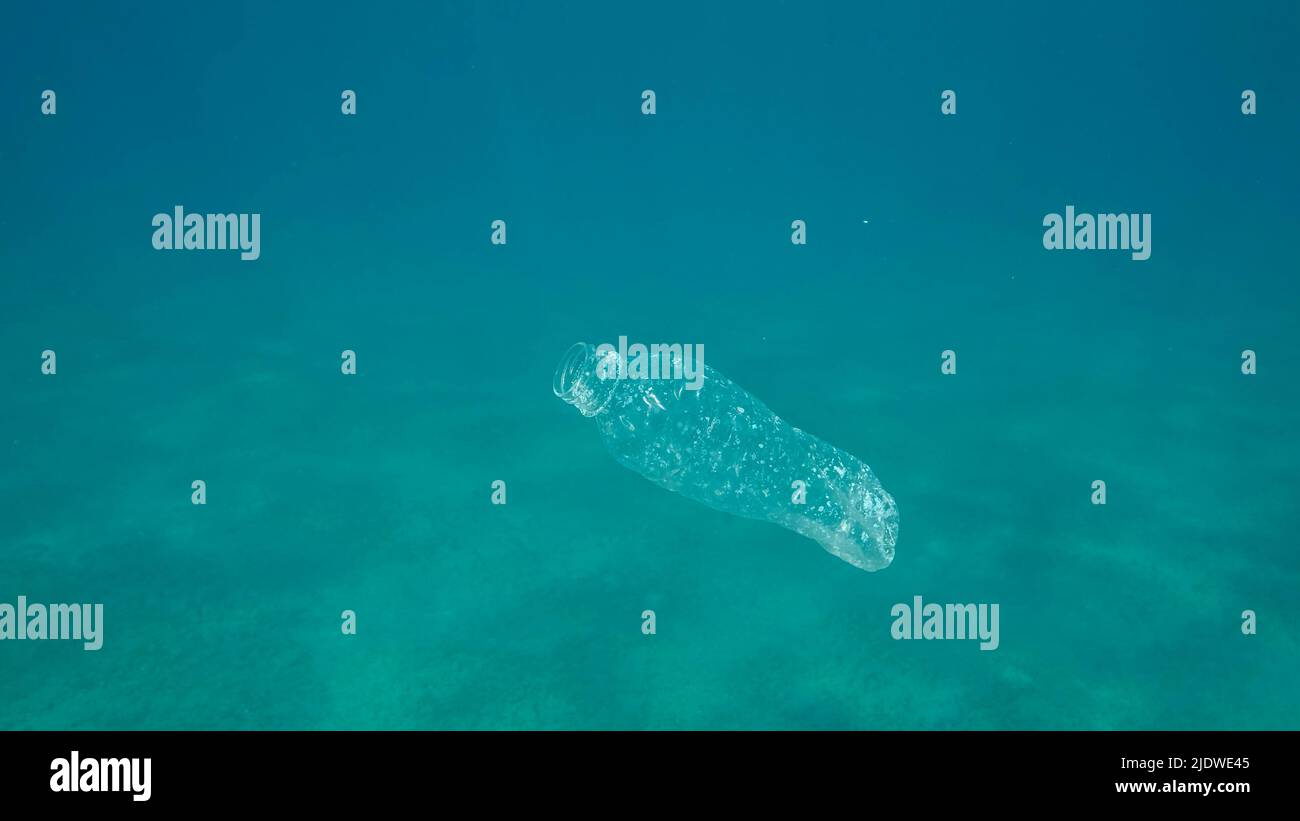 Inquinamento di plastica, bottiglia di plastica in acqua blu. Il flacone di plastica scartato gocciolando lentamente sotto la superficie di acqua blu alla luce del sole. Busta plastica per rifiuti Foto Stock
