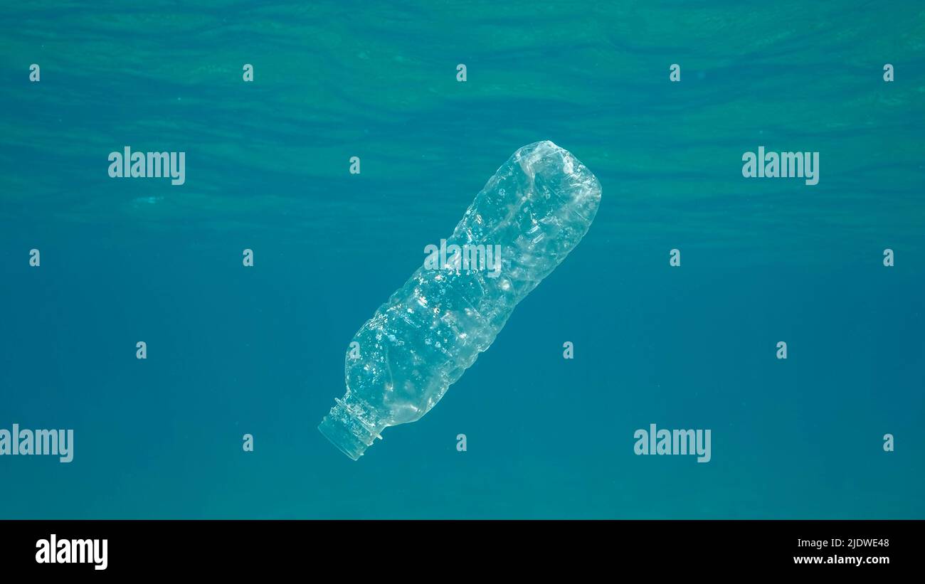 Inquinamento di plastica, bottiglia di plastica in acqua blu. Il flacone di plastica scartato gocciolando lentamente sotto la superficie di acqua blu alla luce del sole. Busta plastica per rifiuti Foto Stock
