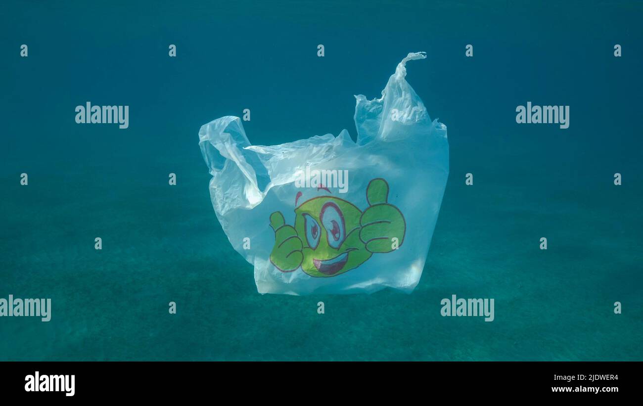 Inquinamento di plastica, sacchetto di plastica bianco usato che si sgocciolano lentamente sott'acqua nelle luci del sole. Movimento lento, detriti di plastica sott'acqua. Inquinamento plastico di t Foto Stock