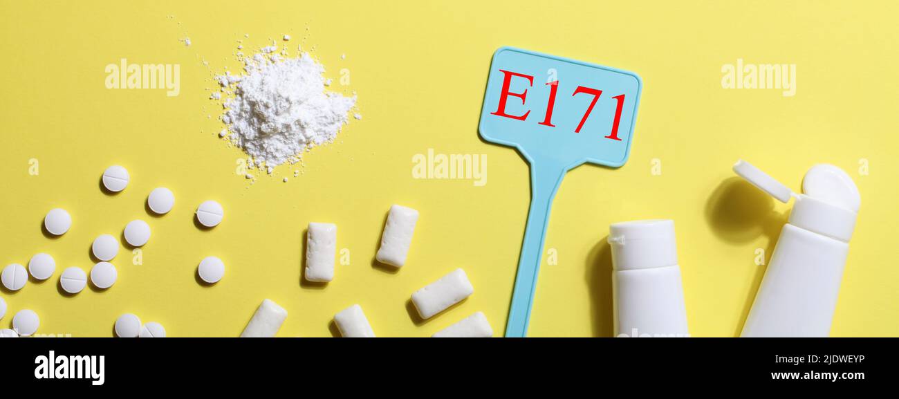 Titanio diossido, E171, additivo pericoloso concetto. Gomma, pillole, dentifricio, polvere e segno con E171 su sfondo giallo. Copia spazio banner Foto Stock