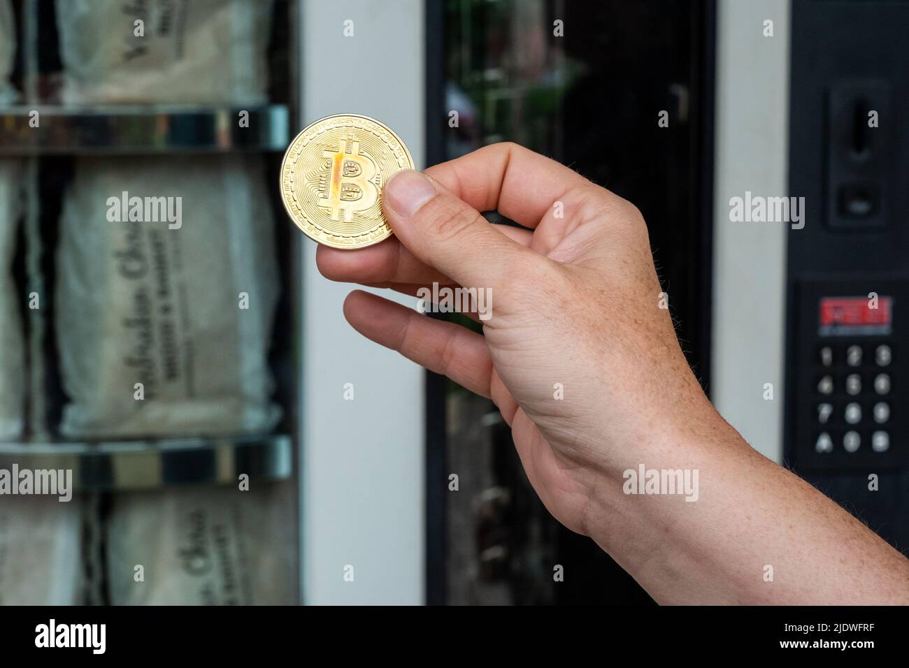 Donna o donna mano che inserisce il bitcoin d'oro nel distributore automatico per comprare il pane o il cibo, concetto finanziario digitale. Foto di alta qualità Foto Stock