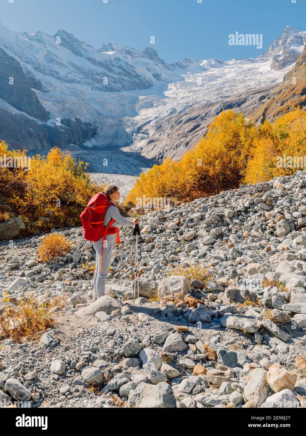 Escursionista con zaino nelle montagne autunnali. Montagna con ghiacciaio e donna escursionista Foto Stock