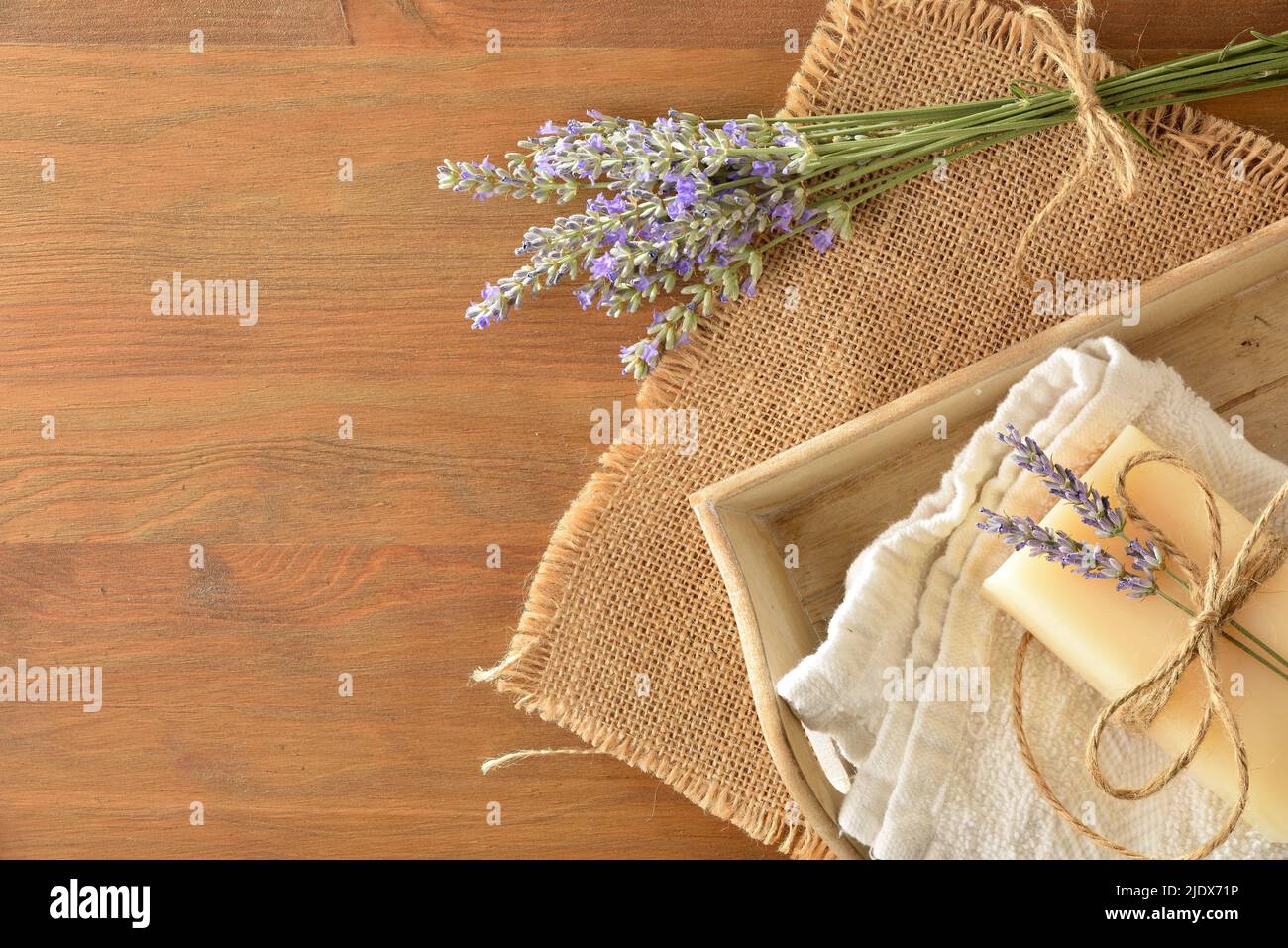 Saponetta di lavanda naturale su asciugamano in vassoio di legno su tavola di legno con bouquet di punte di fiori di lavanda. Vista dall'alto. Composizione orizzontale. Foto Stock