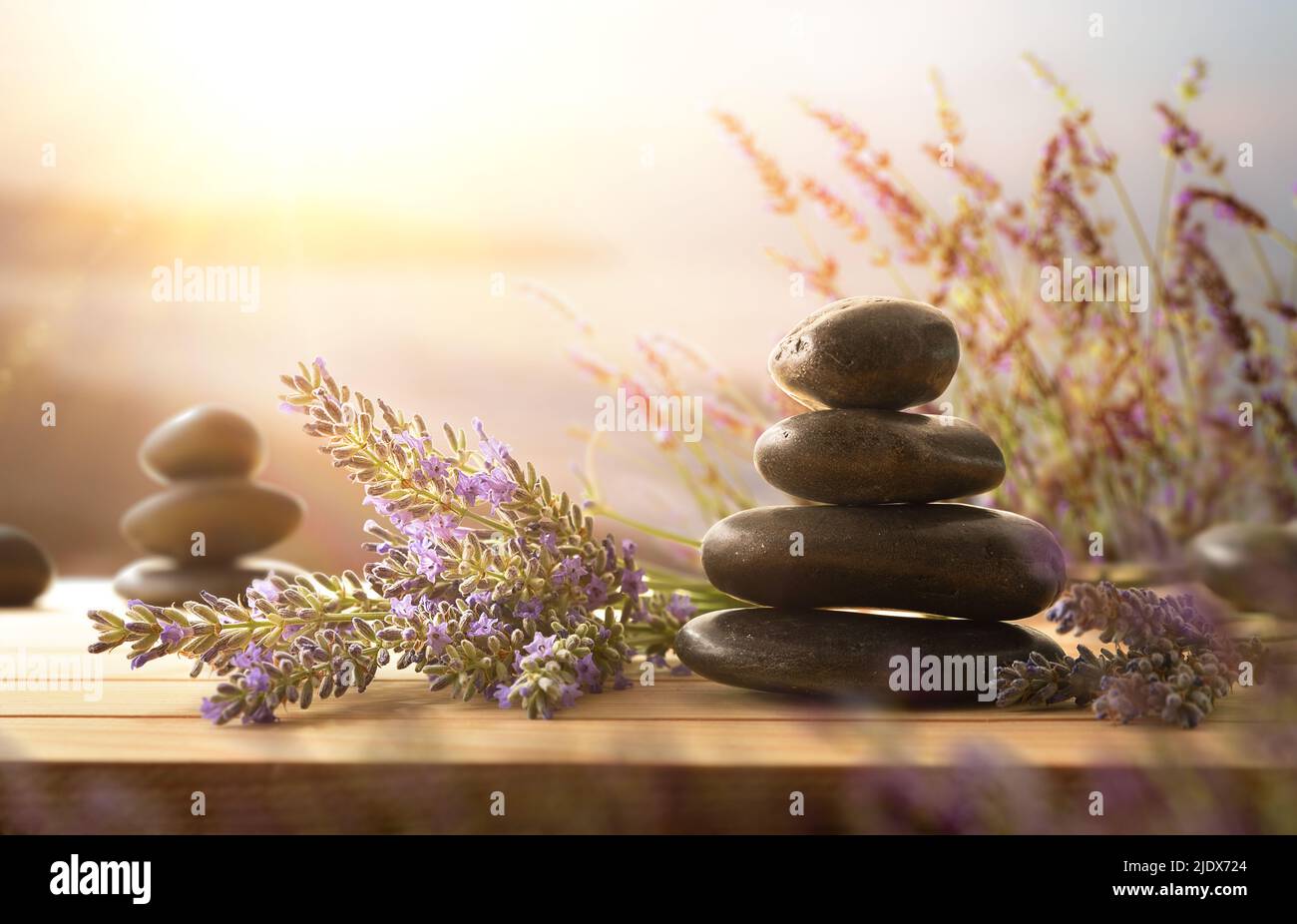 Concetto di relax, meditazione e calma con mucchio di pietre nere su legno e punte di lavanda fiorita con sfondo di paesaggio di mare coa Foto Stock