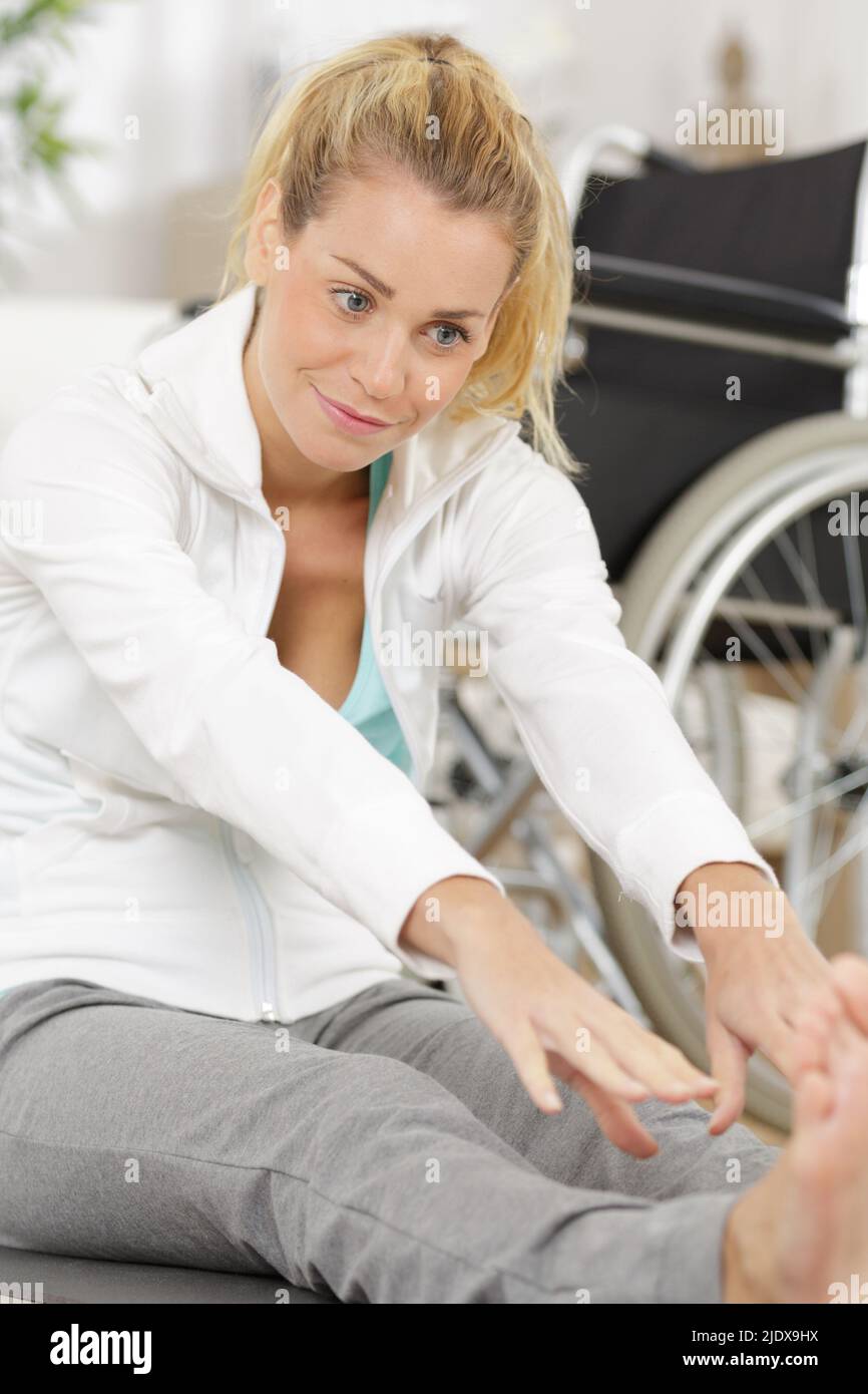 disabilita donna che allunga le gambe in interni Foto Stock