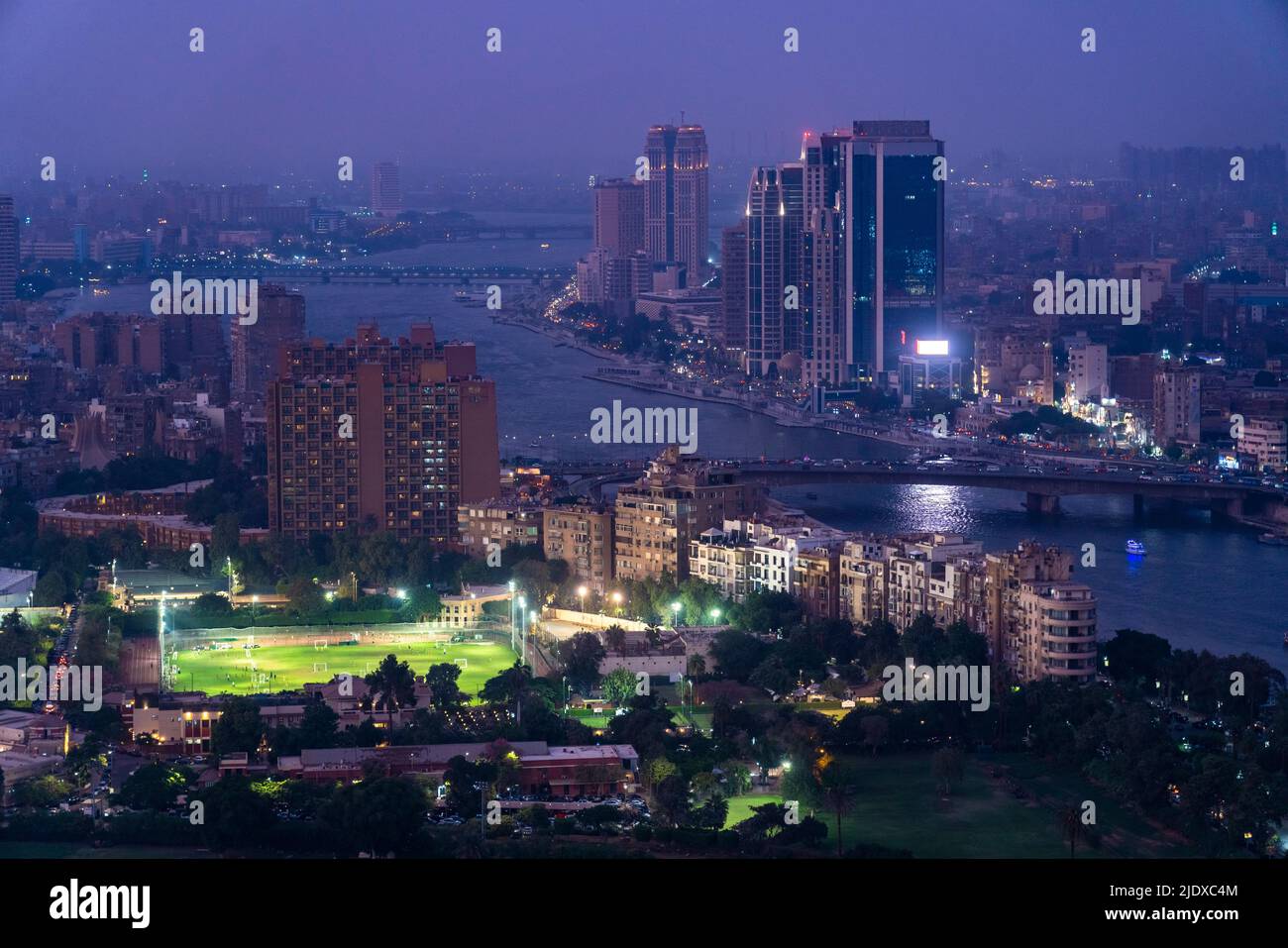 Egitto, Cairo, fiume Nilo, parco della città illuminato al tramonto con il fiume Nilo e grattacieli sullo sfondo Foto Stock