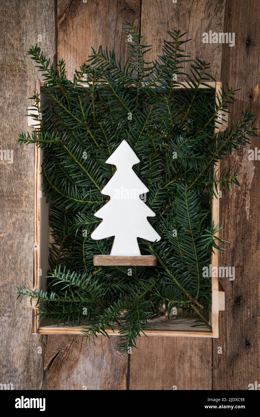 Legno decorazione dell'albero di Natale che giace in gabbia riempita con ramoscelli di conifera Foto Stock