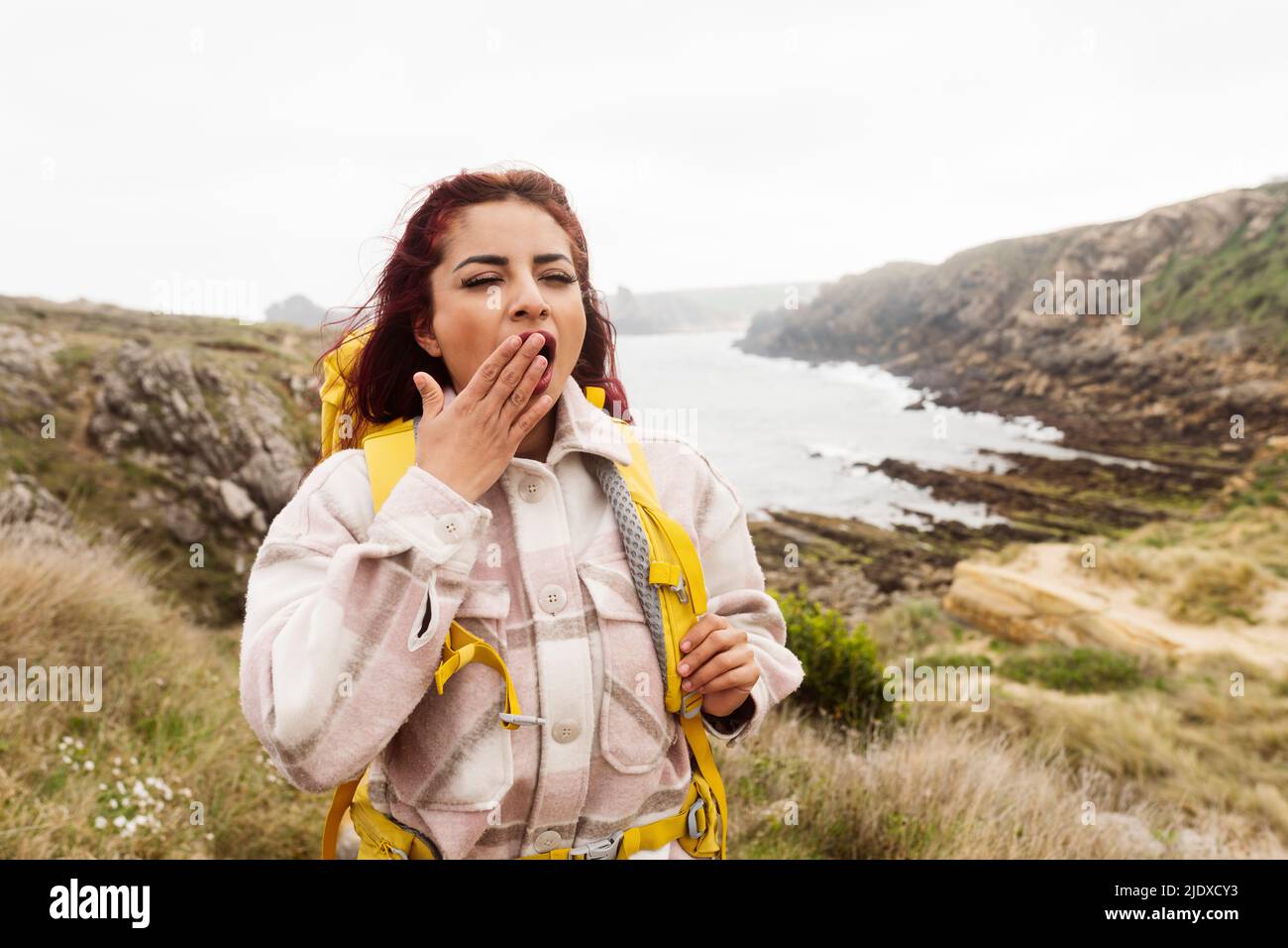 Donna con mano che copre la bocca yawning Foto Stock