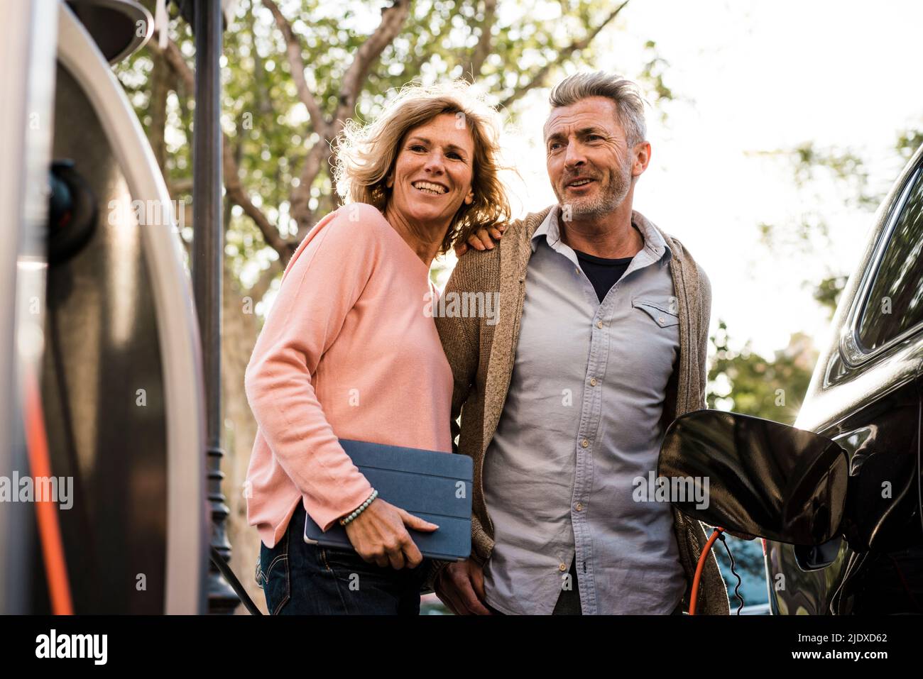 Coppia matura sorridente che guarda la stazione di ricarica Foto Stock