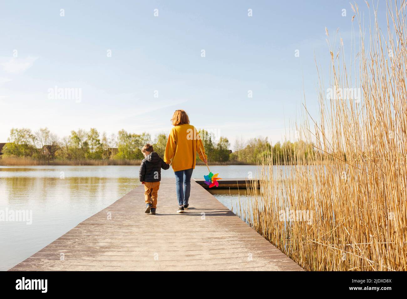 Madre e figlio camminano sul molo sopra il lago Foto Stock